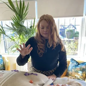 Crystal healing practitioner holding a hand above a treatment table with crystals placed nearby during an energy healing session.